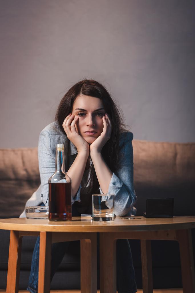 Depressive Frau sitzt allein zu Hause neben Flasche Whiskey - Foto, Bild