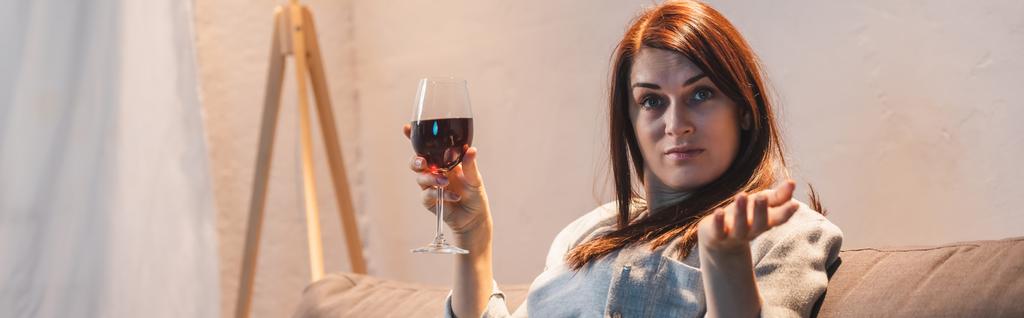 drunk, skeptical woman looking at camera while holding glass of red wine, banner     - Photo, Image