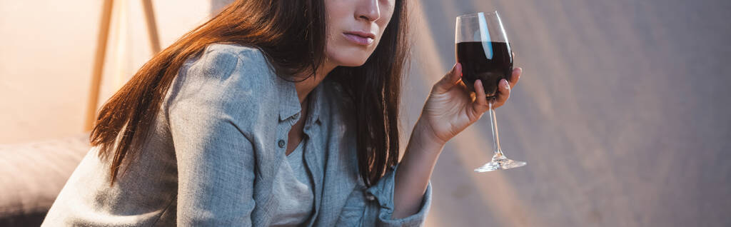 cropped view of alcohol-addicted woman holding glass of red wine, banner  - Photo, Image