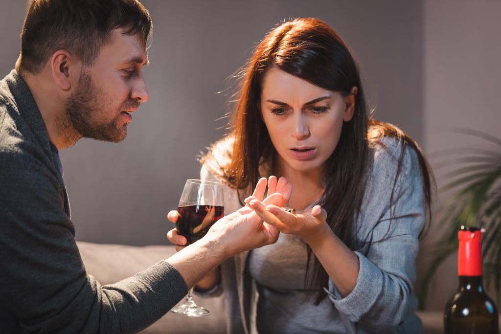 man geven trouwring aan dronken vrouw met glas wijn - Foto, afbeelding