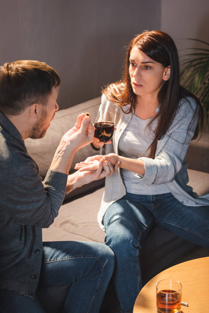 mari donnant une alliance à une femme alcoolique tenant un verre de vin - Photo, image