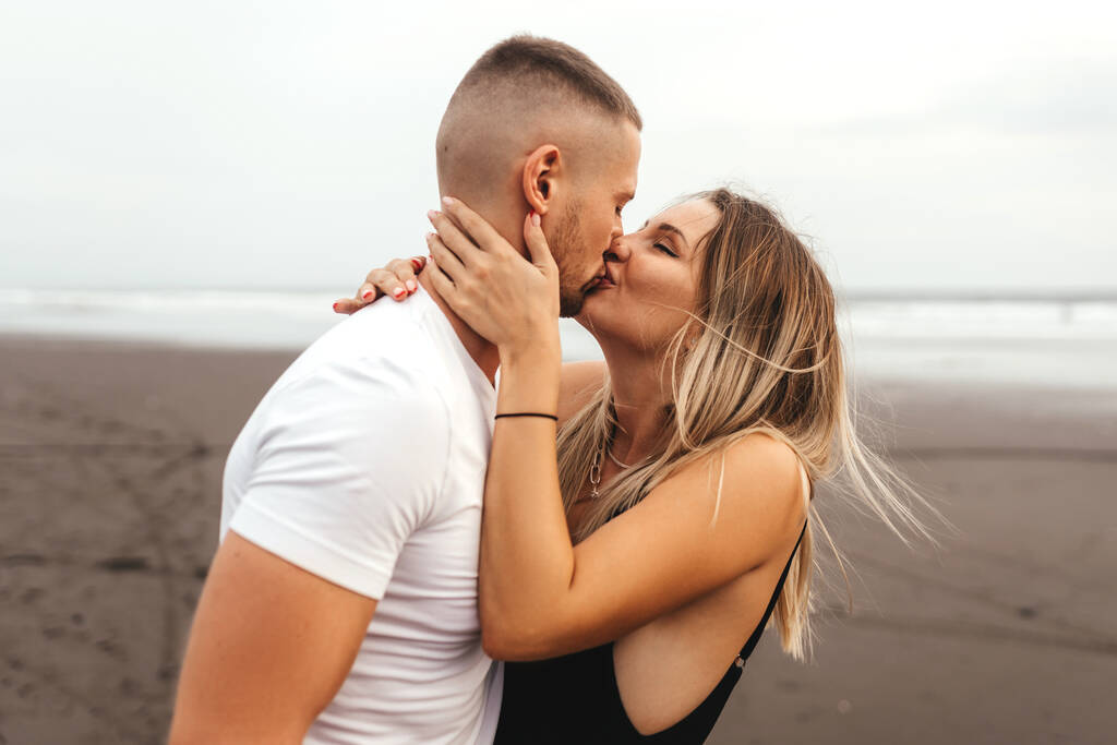 Outdoor shot of smiling young couple walking on beach. - Photo, Image