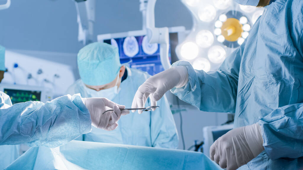 Közelkép a műtőben, asszisztens kiadja a műszereket a sebészeknek a műtét alatt. Műtét folyamatban van. Szakmai Orvosok Végző Sebészet. - Fotó, kép