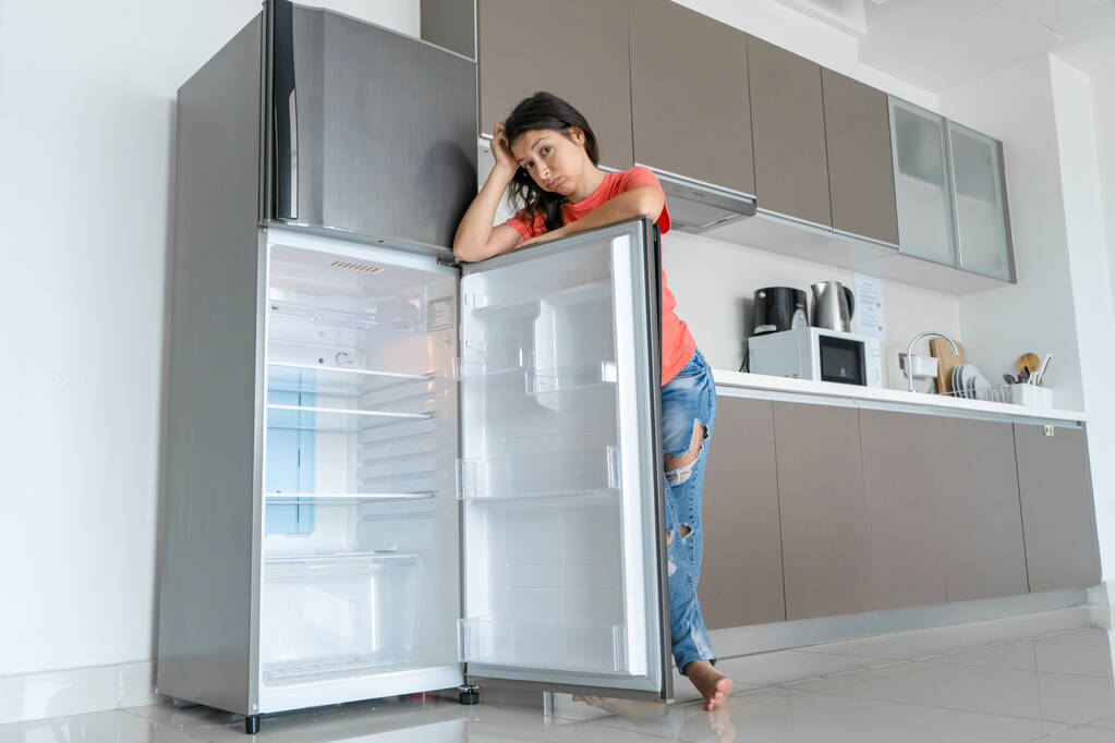 Дівчина здивована порожнім холодильником. Відсутність їжі. Доставка їжі
. - Фото, зображення