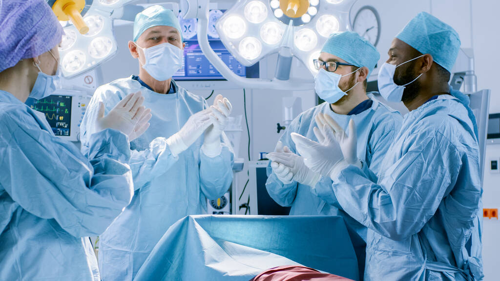 У госпітальній операційній кімнаті Команда різноманітних професійних хірургів та асистентів очікує завершеної хірургії та аплодує успішним результатам. Професійні лікарі успішно врятували життя
. - Фото, зображення
