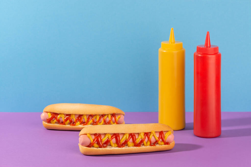 Két szaftos hotdog és préselt üveg mustár és ketchup. - Fotó, kép