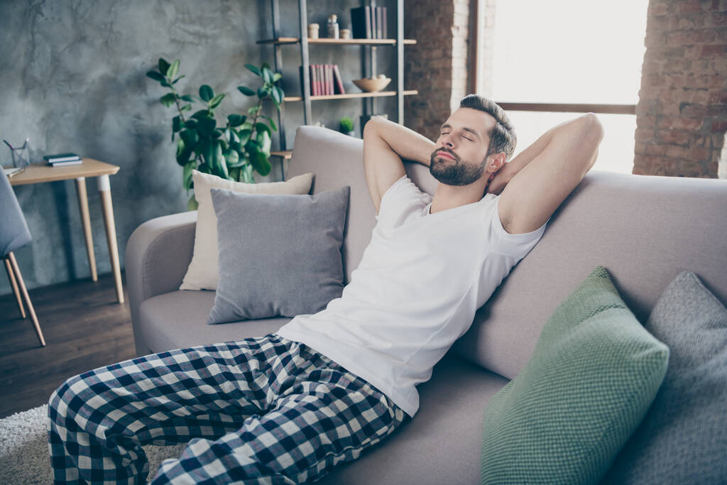Fotografie mírumilovný klidný muž odpočinek relaxovat zavřít oči spánek strečové ruce sedět divan nosit noční oděv spací oděv v bytovém domě vnitřní - Fotografie, Obrázek