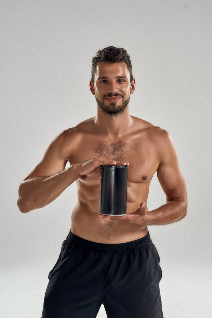 Muscular caucásico hombre mostrando deporte nutrición botella - Foto, Imagen