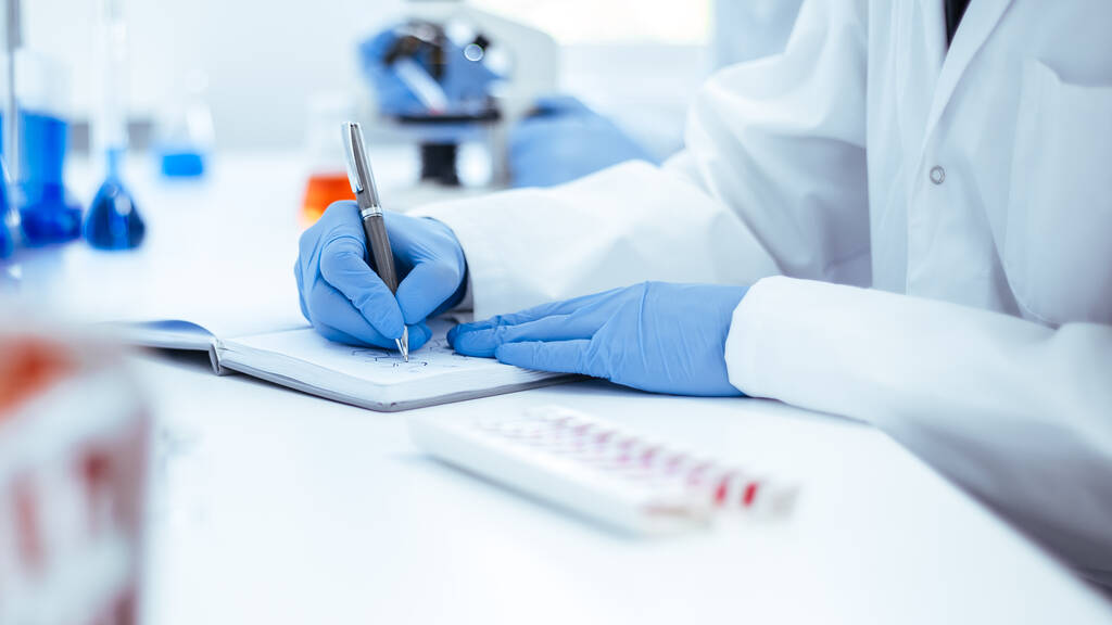 close up. scientist recording the results of the study in a laboratory journal. - Photo, Image