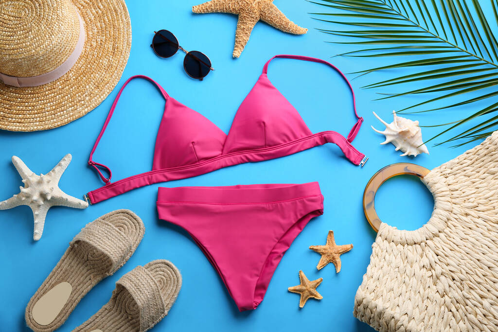 Piękne różowe bikini i akcesoria plażowe na jasnoniebieskim tle, płaska leżanka - Zdjęcie, obraz