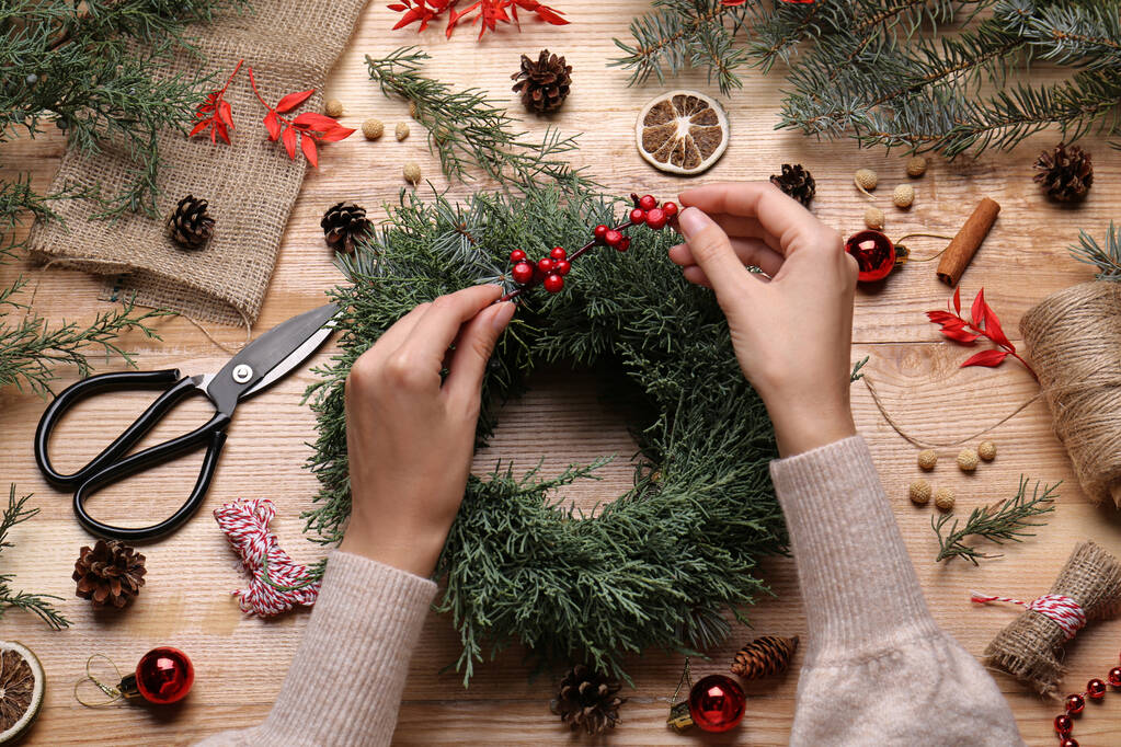 Florist making beautiful Christmas wreath with berries at wooden table, top view - Photo, Image