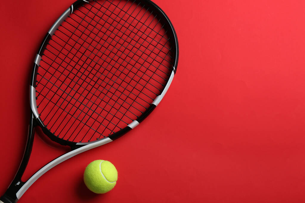Tennisschläger und Ball auf rotem Hintergrund, flach gelegt. Raum für Text - Foto, Bild