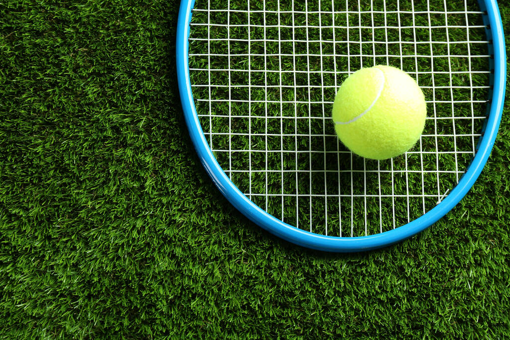 Racchetta da tennis e palla su erba verde, vista dall'alto. Spazio per testo - Foto, immagini