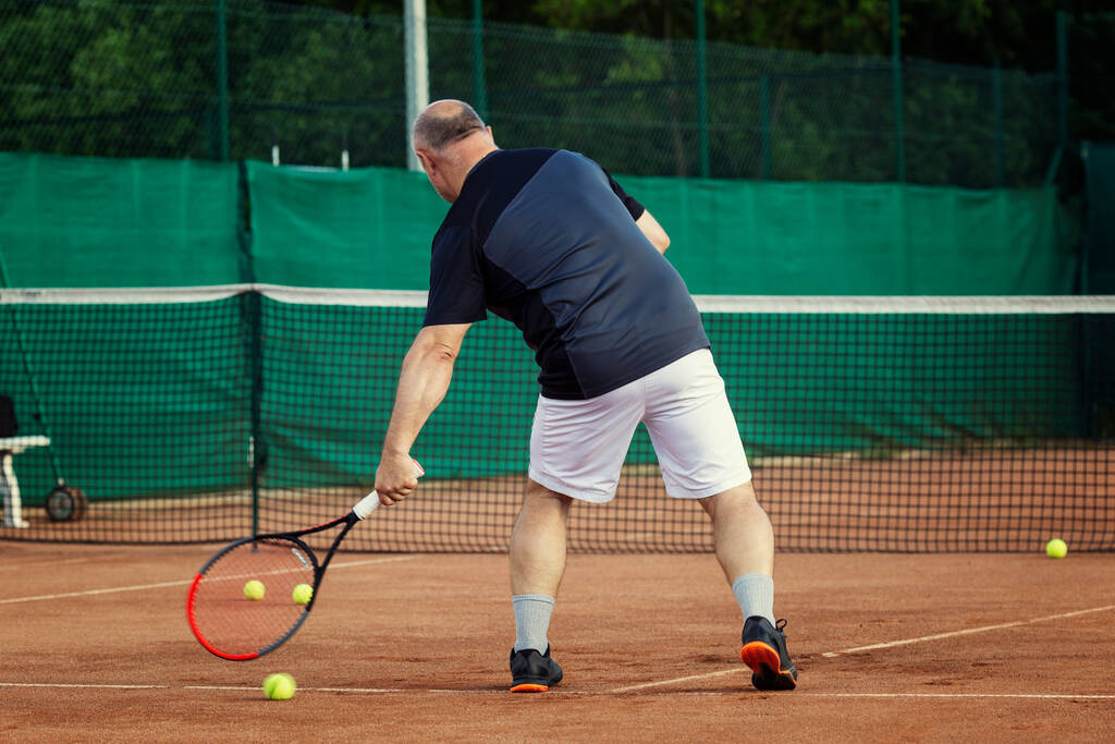 Ikääntynyt mies pelaa tennistä kentällä. Aktiivinen elämäntapa ja terveys. Taustakuva. - Valokuva, kuva