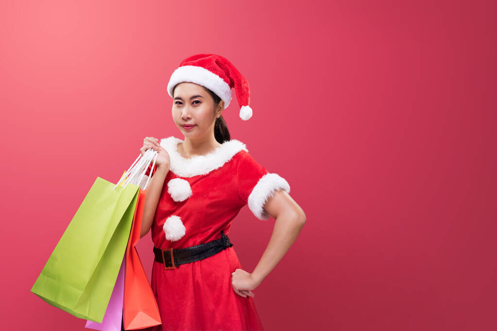 Una bella donna in costume di Babbo Natale che tiene borse della spesa in occasione del Buon Natale e Felice Anno Nuovo. - Foto, immagini