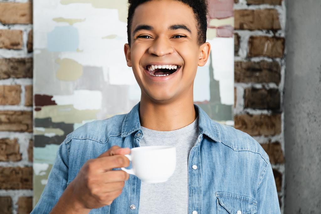 espantado afro-americano homem rindo enquanto segurando xícara de café - Foto, Imagem