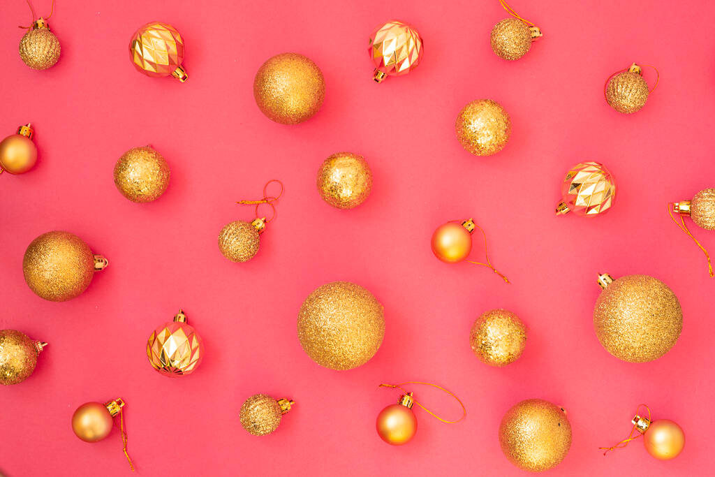 Gouden glitter. Kerstballen van verschillende maten op een roze achtergrond patroon. Vlakke lay, bovenaanzicht. - Foto, afbeelding