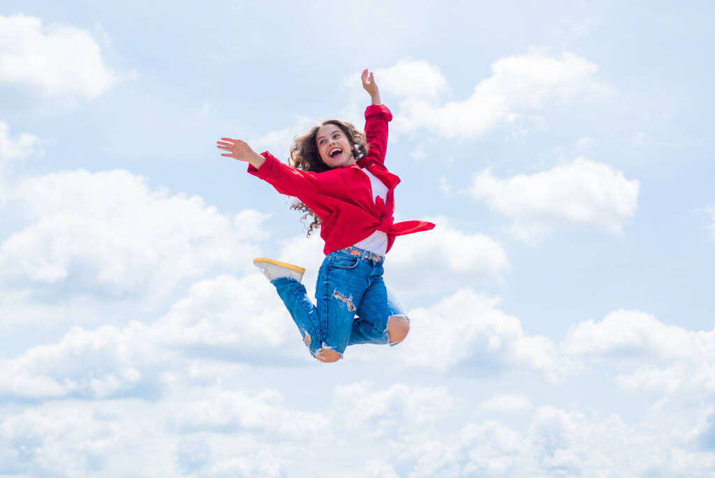 Happy kid wear red jacket. Lifestyle and People Concept. kid spring and fall fashion. full of energy. childhood happiness. teen girl jumping high in the sky. having a party fun - Photo, Image