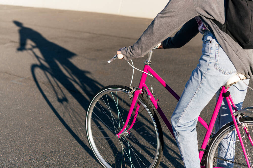 felismerhetetlen fiatal lány, aki rózsaszín retró kerékpárral utazik a városban, az aktív életmód és a fenntartható városi mobilitás koncepciója - Fotó, kép