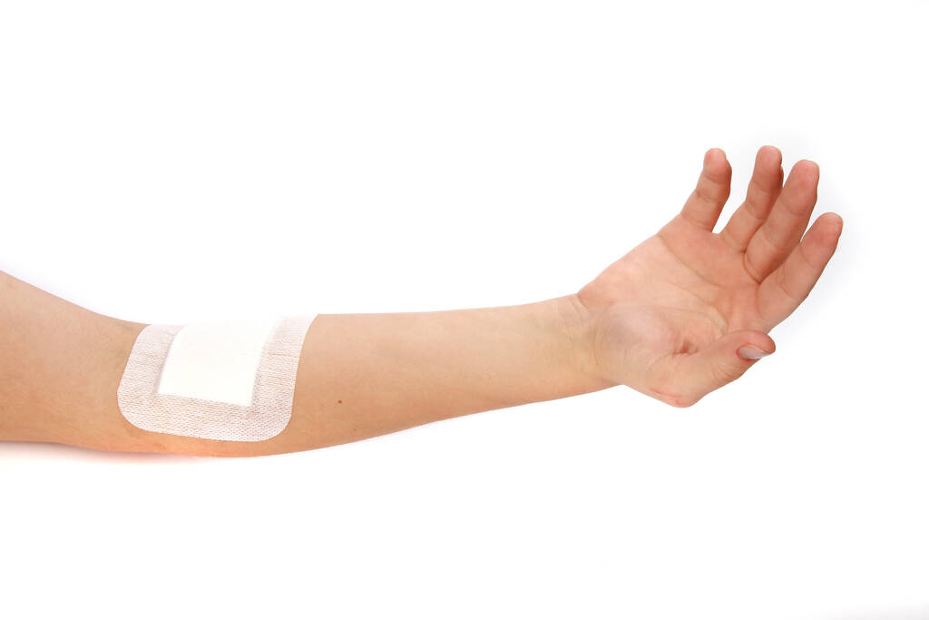 Una inyección de vendajes adhesivos en una mano lesionada aislada sobre un fondo blanco - Foto, imagen
