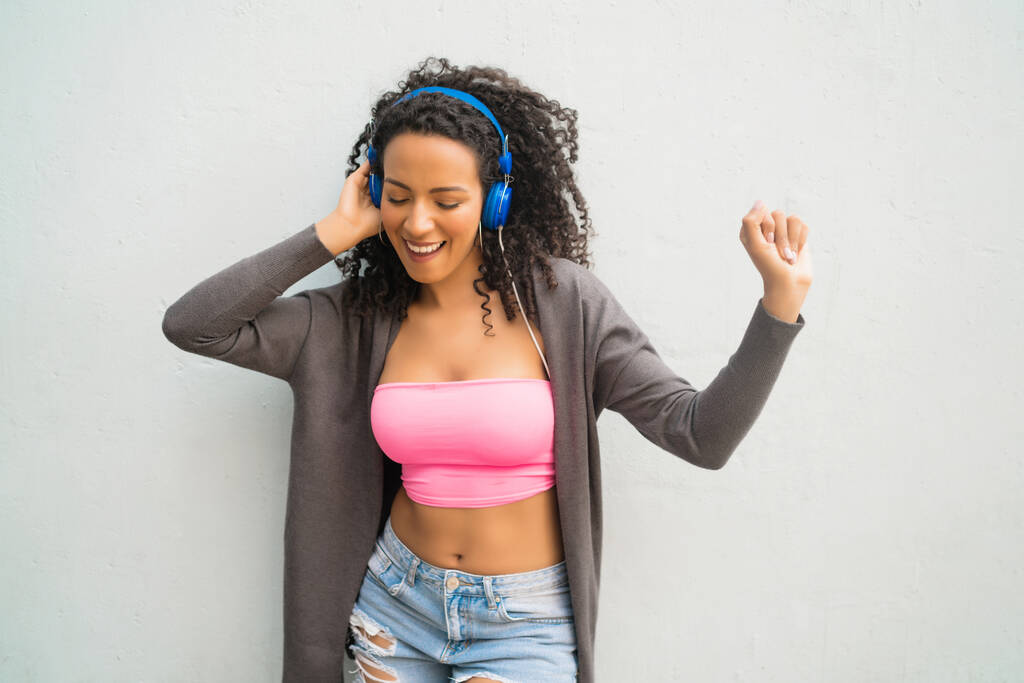 Jovem afro mulher ouvindo música com fones de ouvido. - Foto, Imagem