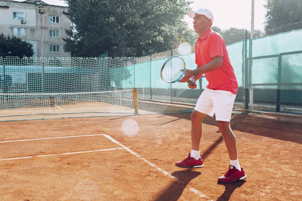 Uomo di mezza età che gioca a tennis su campo da tennis all'aperto archiviato - Foto, immagini