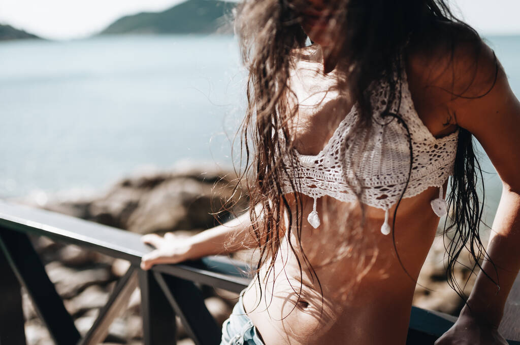 Atraktivní mladá modelka v džínách a bílém top stojící na vile na pláži - Fotografie, Obrázek