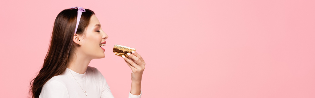 fiatal csinos nő eszik torta elszigetelt rózsaszín, banner - Fotó, kép