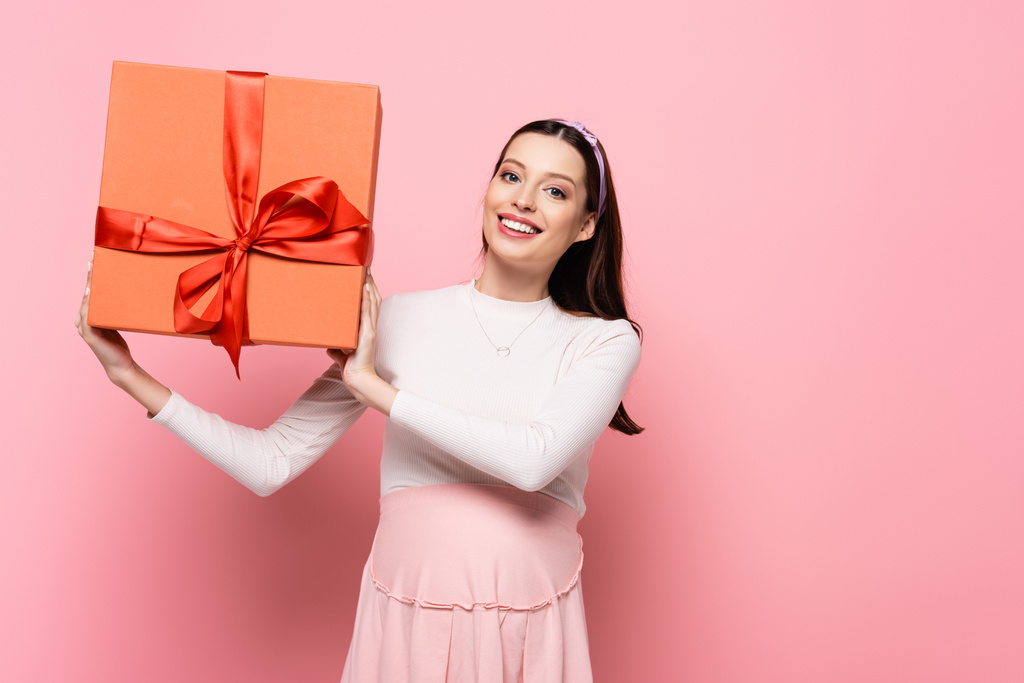 щаслива молода красива вагітна жінка з подарунком ізольована на рожевому
 - Фото, зображення