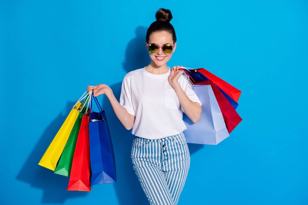Portret van positief vrolijk meisje hebben vrije tijd lopen winkelcentrum kopen hold bags dragen witte stijl stijlvolle trendy outfit geïsoleerd over heldere glans kleur achtergrond - Foto, afbeelding
