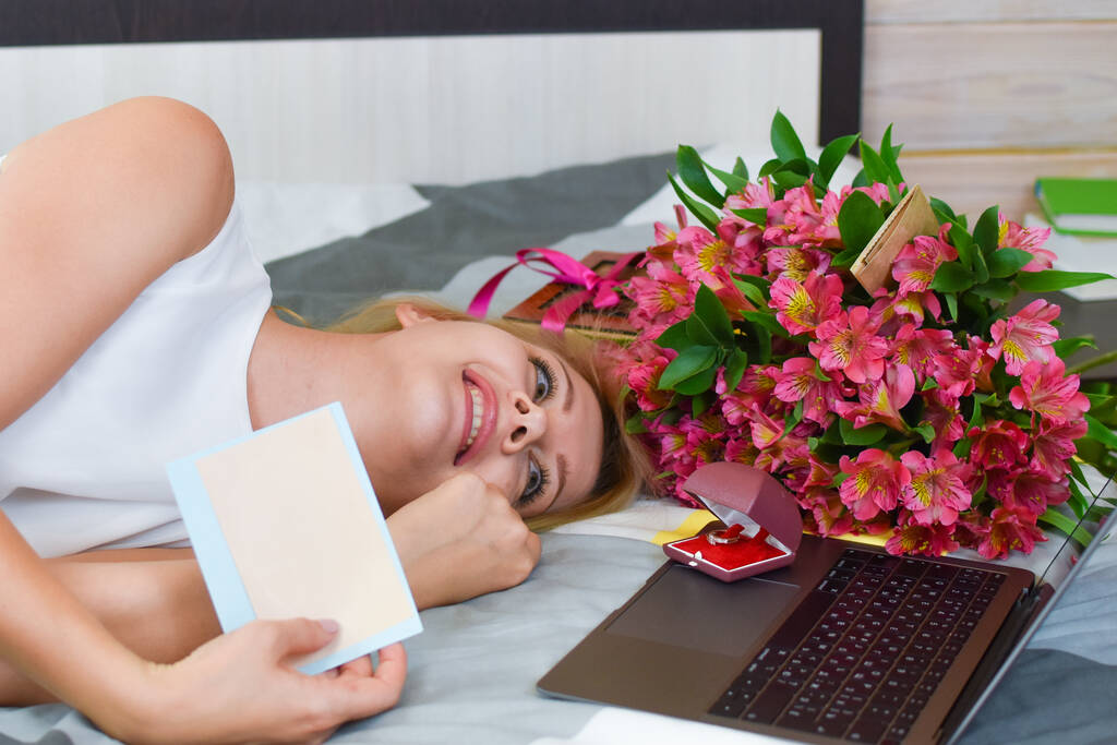 mladá krásná žena leží na posteli s kyticí čerstvých květin. - Fotografie, Obrázek