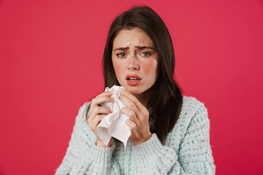 Bild von unglücklich schönen Mädchen mit Grippe hält Serviette isoliert über rosa Hintergrund - Foto, Bild