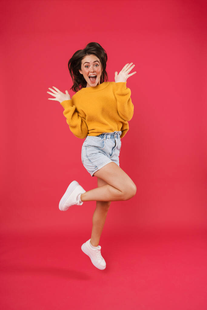 Портрет веселой женщины, прыгающей на розовом фоне - Фото, изображение