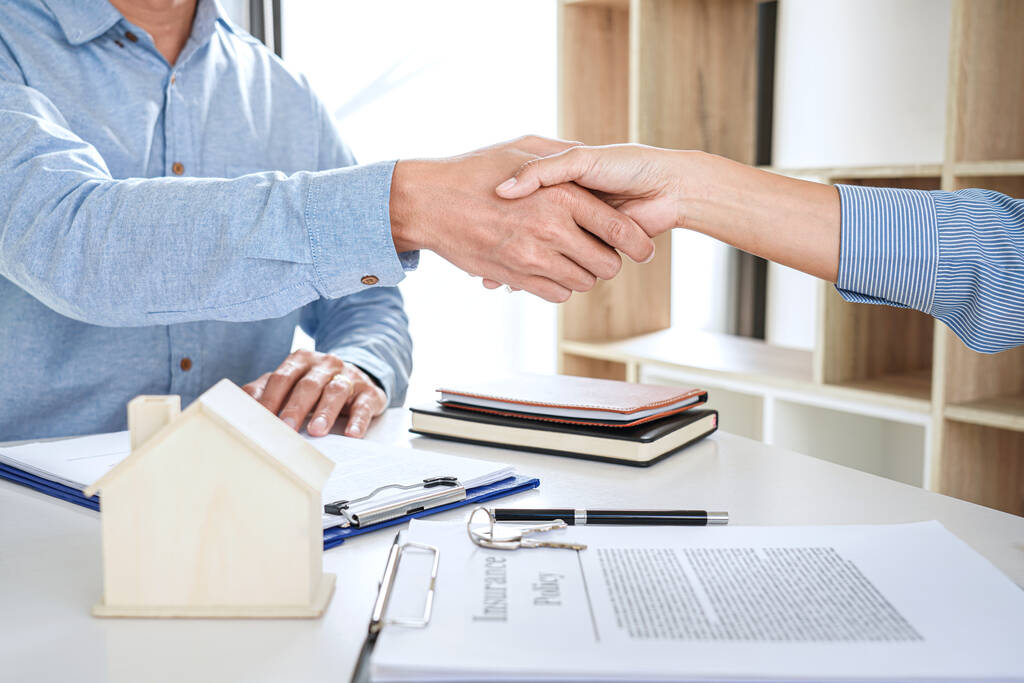 Агент по недвижимости и клиенты пожимают друг другу руки, отмечая завершенный контракт после подписания договора о жилищном страховании и инвестиционном кредите, рукопожатии и успешной сделке. - Фото, изображение