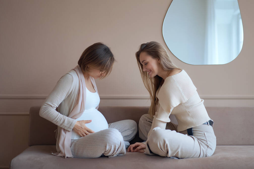 Usmívající se žena dotýkající se břicha těhotné přítelkyně - Fotografie, Obrázek