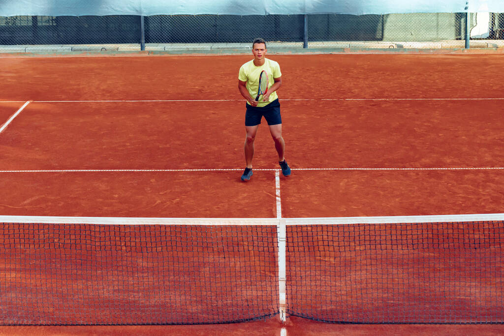 Genç yakışıklı adam tenis kortunda tenis oynuyor. - Fotoğraf, Görsel