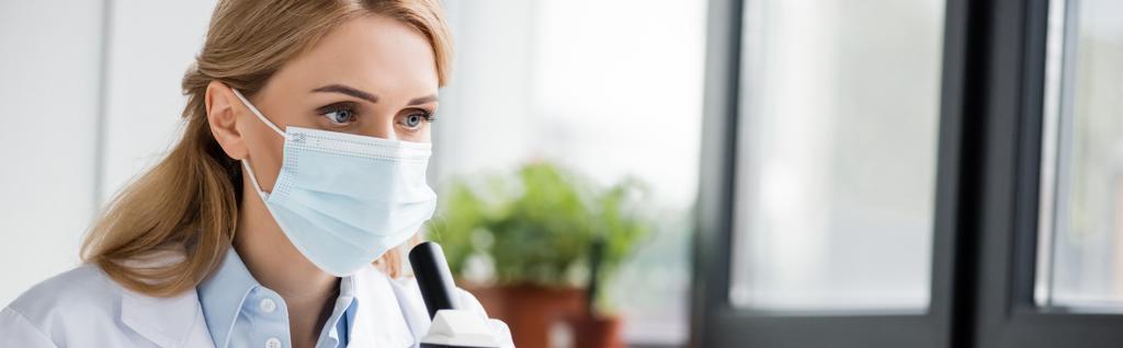 cientista feminino em máscara médica olhando para longe no laboratório, banner - Foto, Imagem