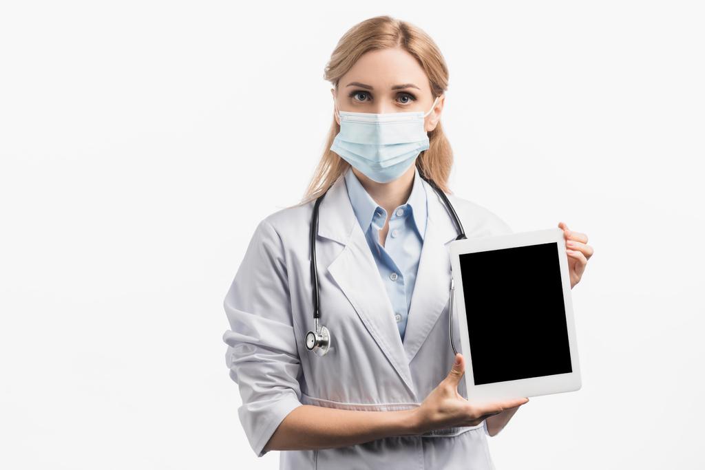 医療用マスクとホワイトコートを着た看護師が白い画面で隔離されたデジタルタブレットを持っています  - 写真・画像
