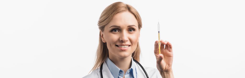 szczęśliwa pielęgniarka w białym fartuchu trzymająca strzykawkę ze szczepionką wyizolowaną na białym, banerze - Zdjęcie, obraz