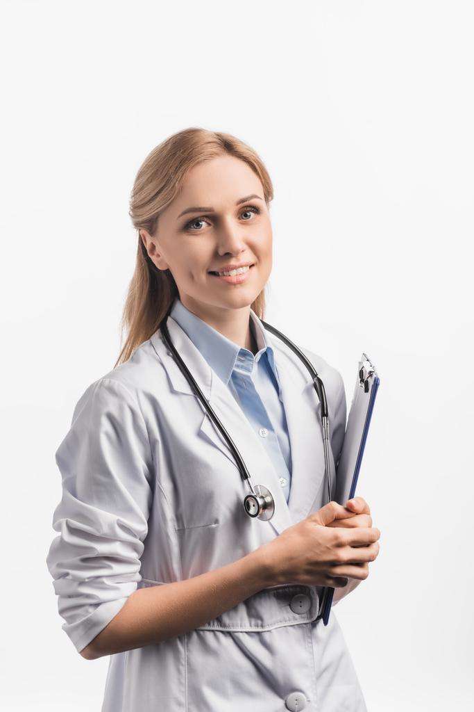 happy nurse in white coat holding clipboard isolated on white - Photo, Image