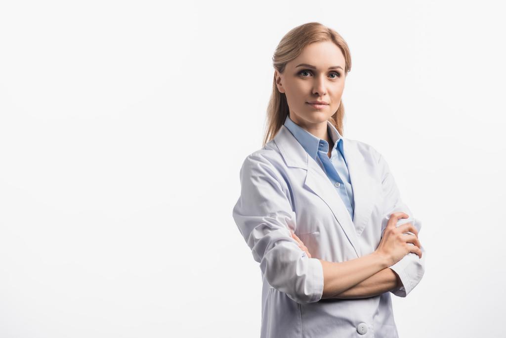 enfermeira confiante em casaco branco de pé com braços cruzados isolados em branco - Foto, Imagem