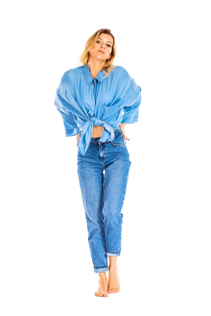 Портрет блондинки в синих джинсах и рубашке на белом фоне - Фото, изображение