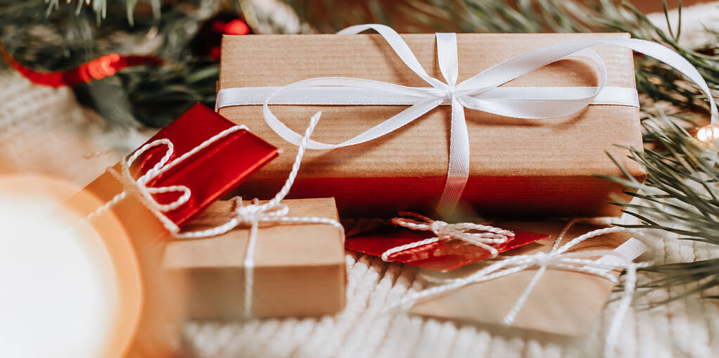 Neujahrsgeschenke auf gestricktem Hintergrund mit Weihnachtsbaum und Spielzeug im Licht - Foto, Bild