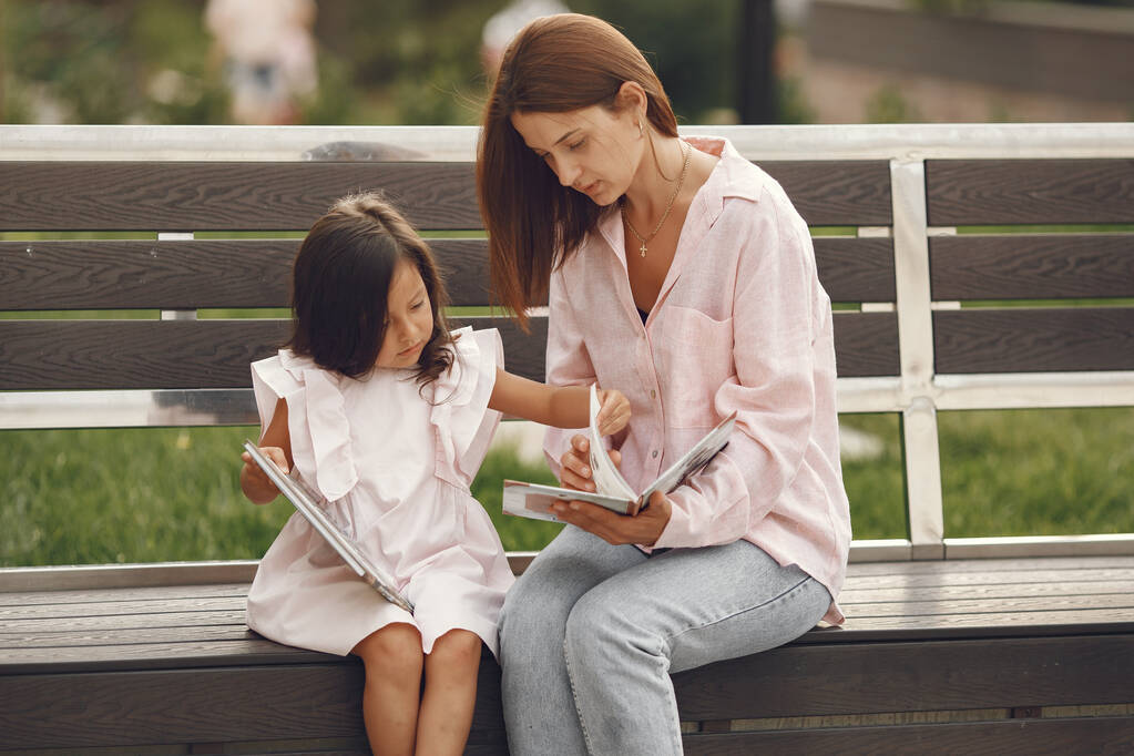 Anne ve kızı şehirde kitap okuyorlar. - Fotoğraf, Görsel