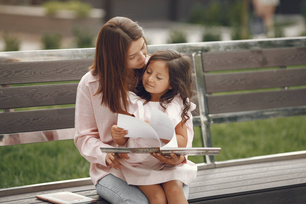 Madre con figlia che legge un libro in città - Foto, immagini