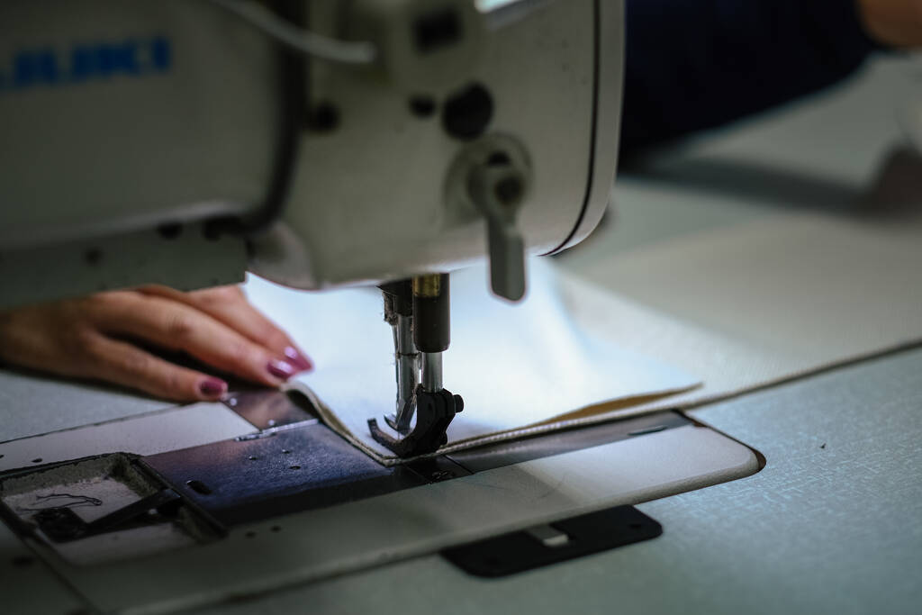 Un primer plano de una mujer operando una máquina de coser industrial - Foto, Imagen