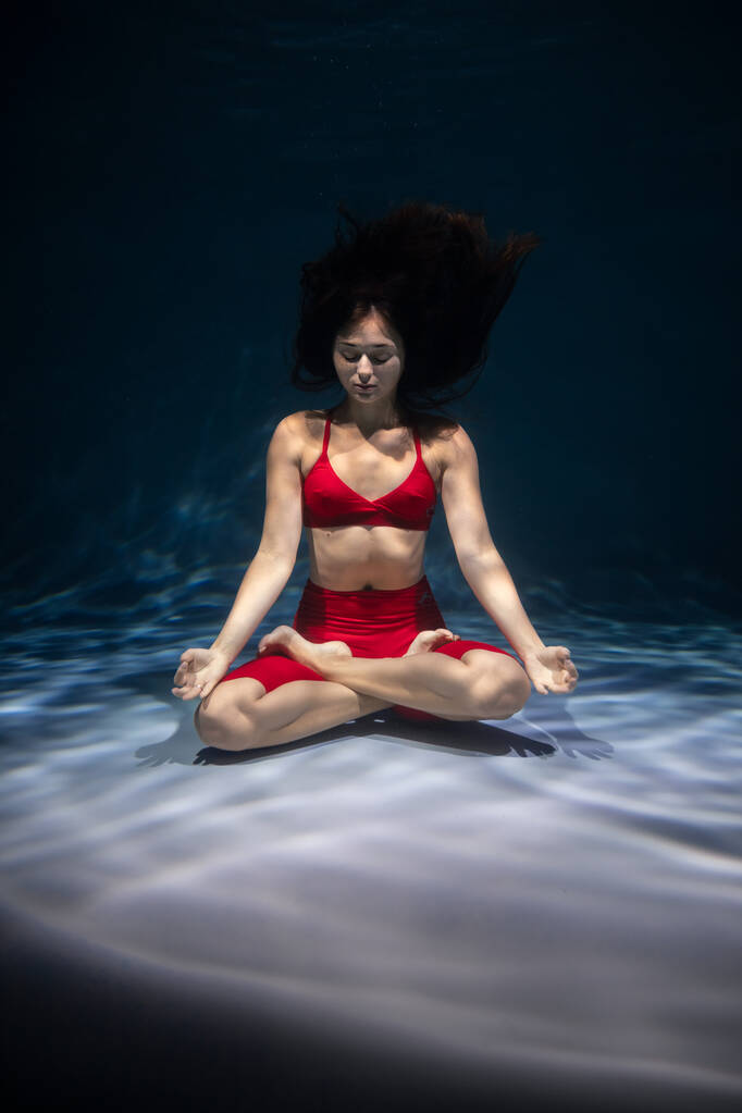 A lány sportruhában jógázik a víz alatt. Elmerülés a meditációban - Fotó, kép