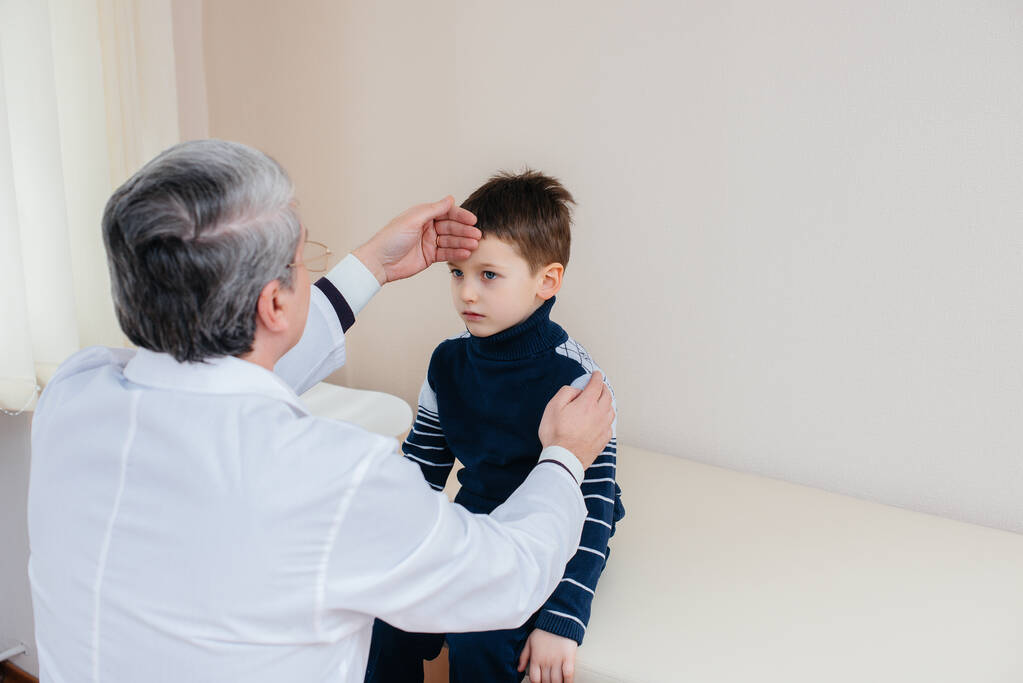 Ein kleiner Junge wird von einem erfahrenen Arzt in einer modernen Klinik behandelt. Ein Virus und eine Epidemie - Foto, Bild