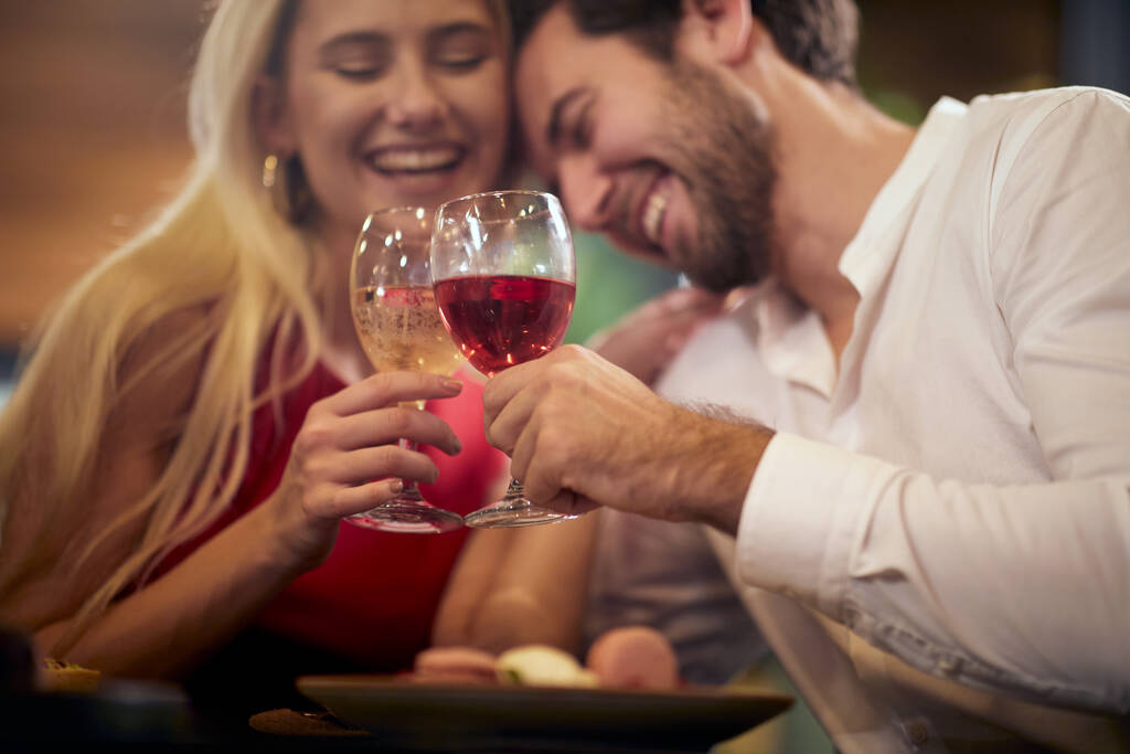 Nuori pariskunta rakastuneena nauttimassa drinkistä ystävänpäivän juhlissa rennossa ilmapiirissä ravintolassa. Yhdessä, ystävänpäivä, juhla - Valokuva, kuva