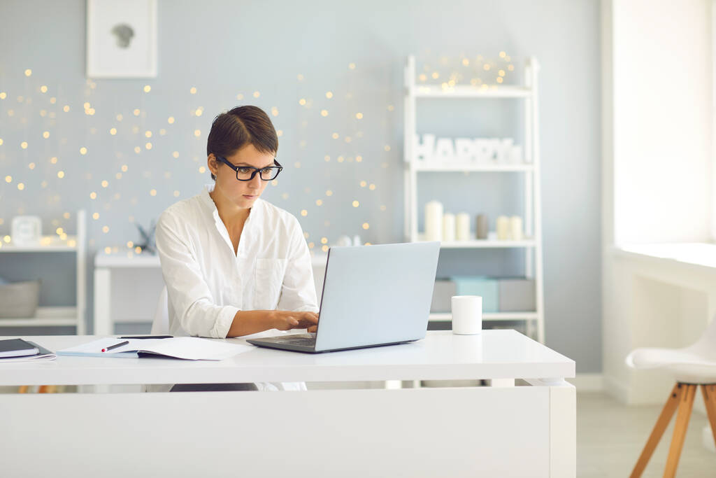 Obchodní dáma v brýlích sedí doma a pracuje na notebooku on-line - Fotografie, Obrázek